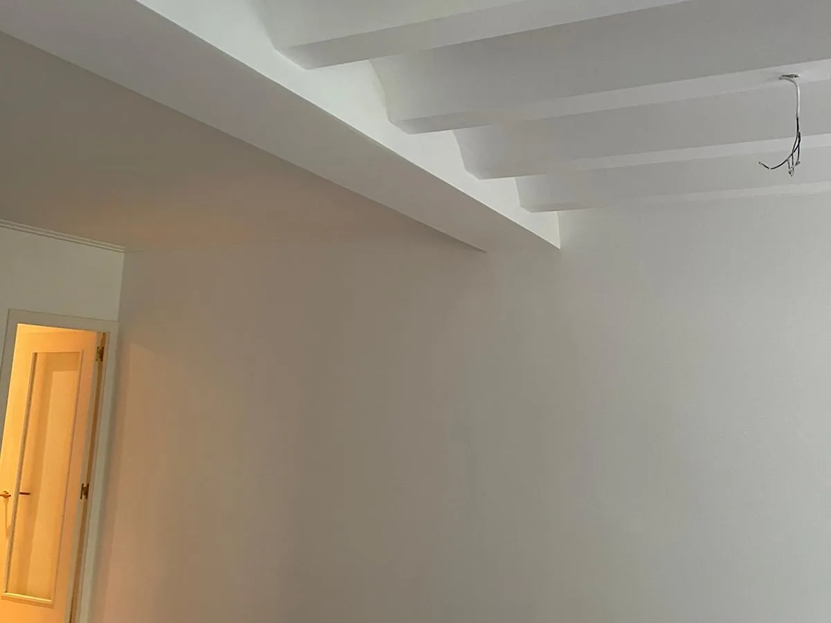 Estancia recién pintada en blanco con vigas en el techo